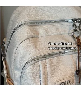 Détail d'un sac à dos blanc en cuir grainé avec fermetures éclair et multiples poches