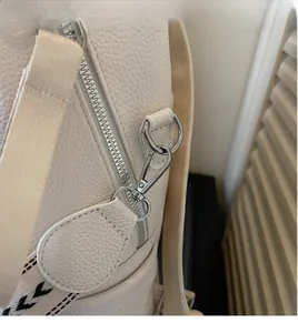 Detailed macro view of cream-white lychee grain leather backpack with silver metal hardware