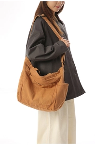 Caramel brown large canvas crossbody bag with side pockets and adjustable strap shown on model