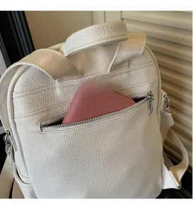 Detailed view of the back anti-theft zipper pocket on a white leather backpack