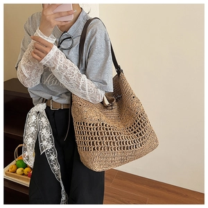 Détail du sac cabas en paille tressée avec bandoulière en cuir et bouton en bois