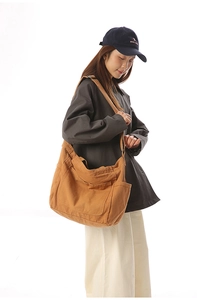 Detail view of large brown canvas crossbody bag with side water bottle pocket and wide strap