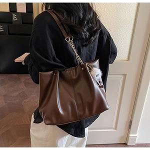 Detailed back-side view of large brown PU leather tote bag with chain strap and plush charm