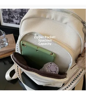 Detail view of white lychee leather backpack showing large zipper pocket and spacious interior
