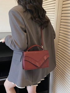 Sac bandoulière minimaliste en cuir bordeaux avec franges en V porté par un mannequin