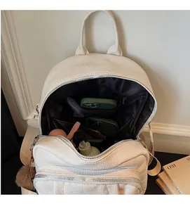 Vue intérieure du sac à dos en cuir blanc montrant les compartiments et poches spacieux