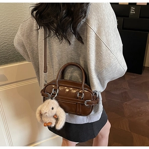 Detail of dark brown glossy Boston bag with silver hardware and plush bunny charm