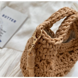 Détail du sac en paille tissé main montrant la texture et le fermoir mousqueton doré
