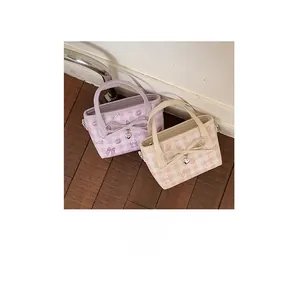 Close-up of checked texture handbags with bow detail and heart pendant on wood floor