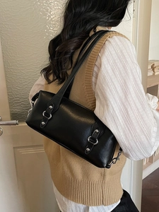 Minimalist black PU leather underarm bag with silver rings shown on a model in an indoor setting