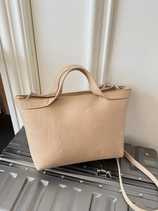 Minimalist cream faux leather tote bag on silver suitcase for daily commuting