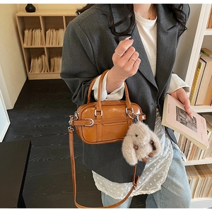 Detail view of a vintage brown leather Boston bag with a cute plush bunny charm