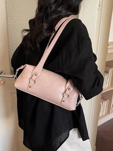 Chic pink cylinder shoulder bag in glossy leather worn by a woman for a stylish look