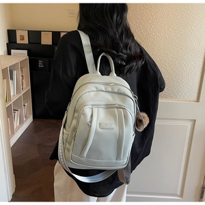 Détail du sac à dos vert menthe en similicuir avec pompon et bandoulière tissée chic