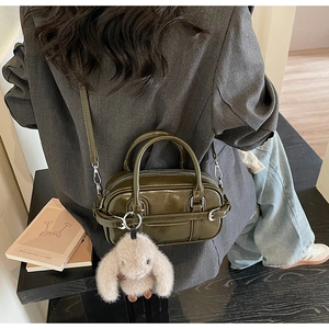 Detailed olive green mini handbag with smooth finish and cute plush bunny charm