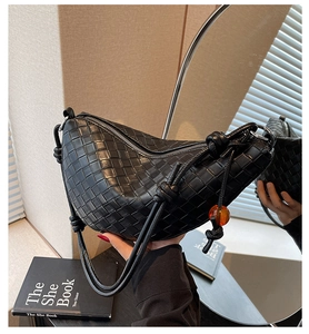 Détail du sac croissant en cuir tressé noir avec perle ambrée et bandoulière nouée