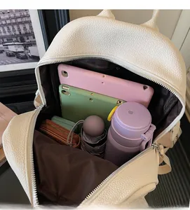 Detail view of white lychee leather backpack showing large capacity and internal storage
