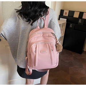 Vue détaillée du sac à dos rose en cuir PU avec texture grainée et pompon décoratif