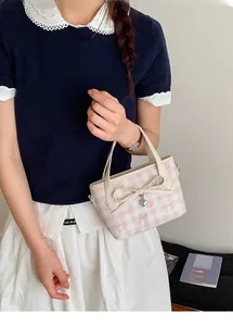 Detailed close-up of pink and white gingham bucket bag with a leather bow and heart pendant