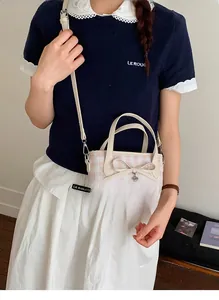 Detail of pink plaid bucket bag with butterfly bow and heart pendant on a model