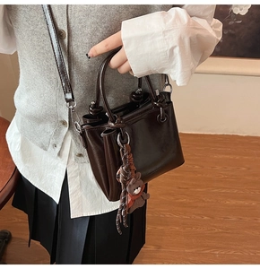 Detalle del bolso bombonera café vintage con asa anudada y colgante de oso decorativo
