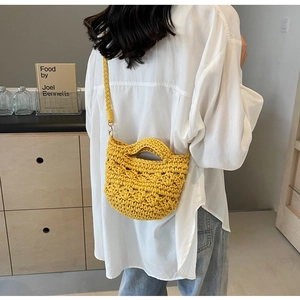 Détail du sac en paille jaune crocheté à la main avec motifs ajourés portés par le mannequin