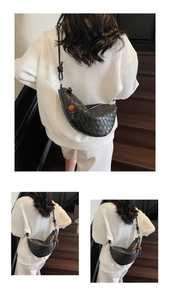 Détail du sac croissant tressé noir avec perle orange porté par un mannequin ici