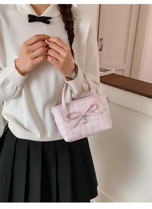 Detail of light pink crossbody bucket bag featuring butterfly embossed Sanrio patterns