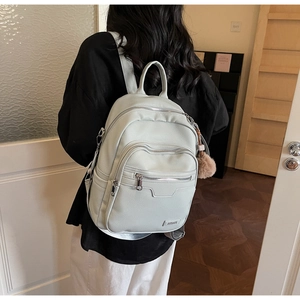 Close-up of light blue pebbled leather backpack with plush charm and metal mmi logo