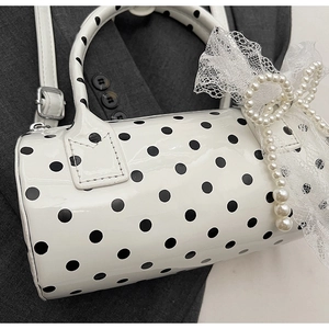 Detailed close-up of polka dot Boston bag with lace bow and pearl charm accessories