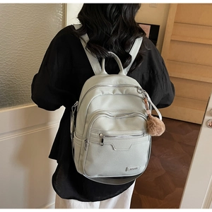 Close-up of light green backpack with lychee pattern leather and plush pompom charm