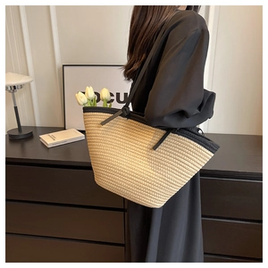 Detail view of large straw tote bag with black faux leather trim and long shoulder straps