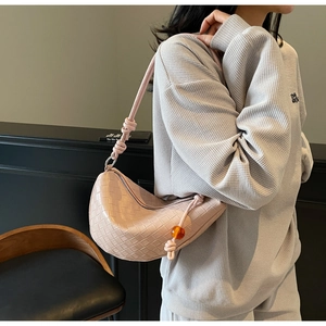 Detail of light pink woven hobo bag with knotted strap and amber bead charm