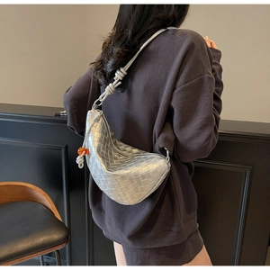 Détail du sac demi-lune tressé argenté avec bandoulière à nœud et perle orange