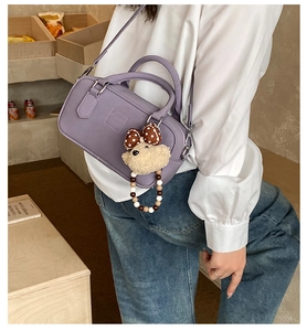 Détail du sac Boston violet avec pendentif ours en peluche et nœud à pois sur un modèle
