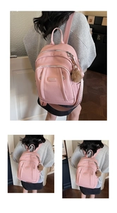 Détail du sac à dos en cuir rose avec logo en métal et accessoire boule en peluche