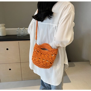 Détail d'un sac de plage tressé orange vif avec poignées intégrées et bandoulière souple