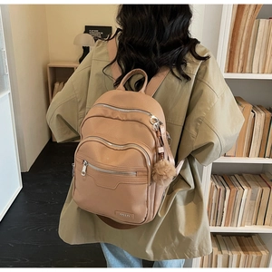 Detail showing litchi grain faux leather and metallic logo on khaki fashion backpack