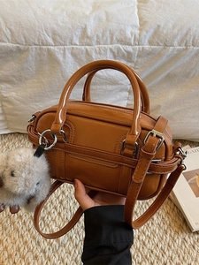 Brown mini Boston bag with plush fur ball charm and adjustable shoulder strap
