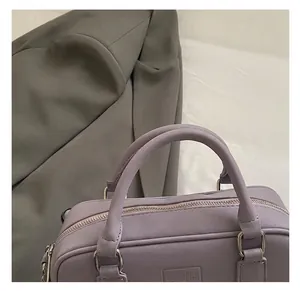 Detail of purple faux leather bowling bag featuring COIH embossed logo and sturdy handles