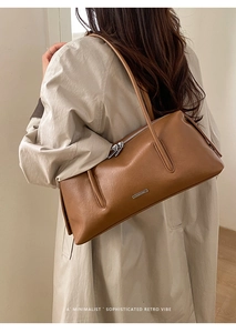 Detailaufnahme der braunen Leder-Baguette-Tasche mit Silberlogo auf beigem Trenchcoat