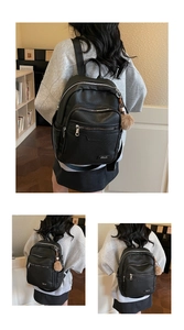 Close-up of black lychee texture faux leather backpack with silver metal logo and plush charm