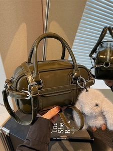 Deep olive green glossy leather Boston bag with plush rabbit charm and crossbody strap