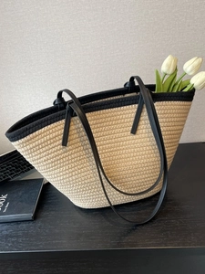 Straw woven tote bag with black trim and long shoulder straps for beach vacation style