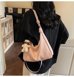 Detail of soft pink hobo bag with unique knot shoulder strap and cute bear charm pendant