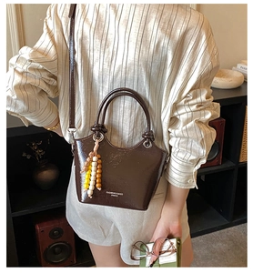 Détail d'un sac seau en cuir verni marron foncé avec charm en perles de bois colorées