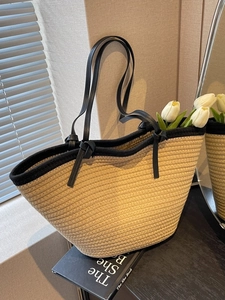 Minimalist straw woven tote bag with black trim and long shoulder straps for beach vacation