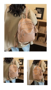 Close-up of a light brown lychee grain leather backpack with a plush pom-pom keychain