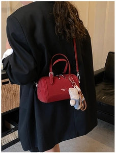 Red cylindrical Boston bag with bear charm shown from behind on a model's shoulder