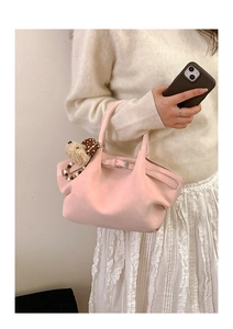 Detalle de bolso cubo de cuero rosa con textura plisada y colgante de cachorro